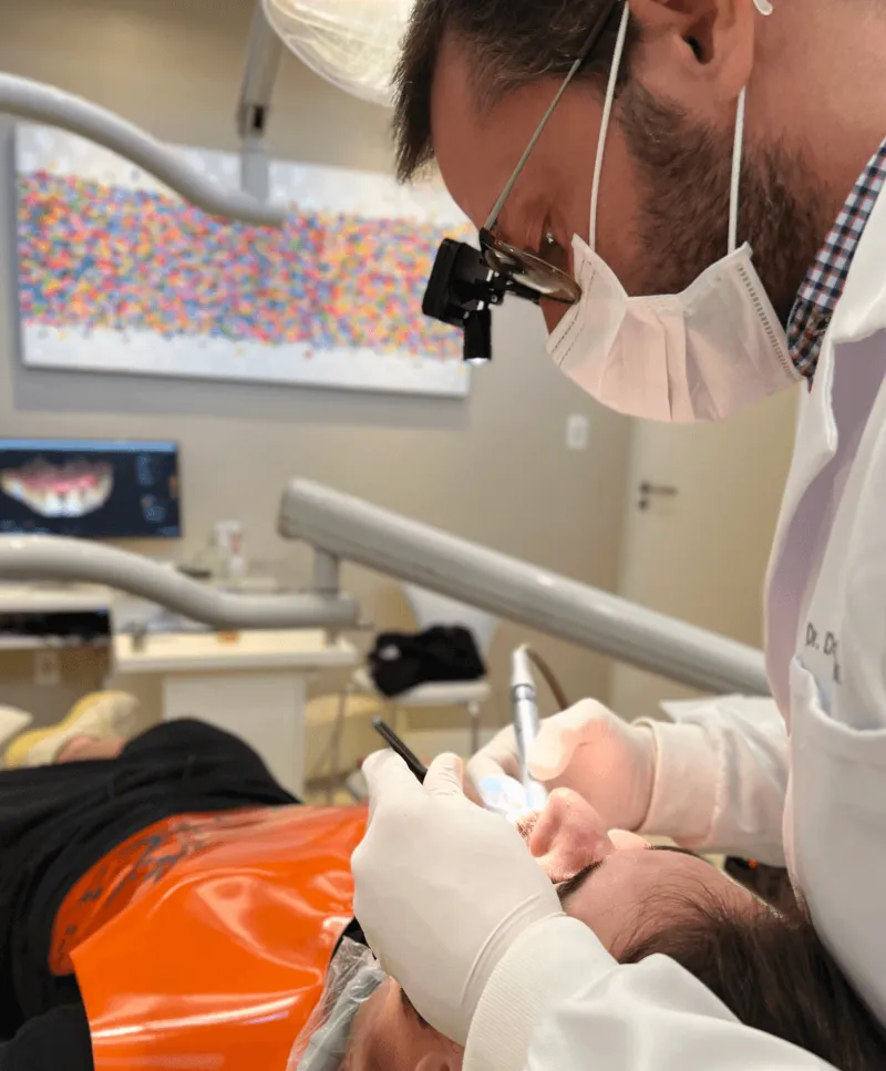 Dentista da Clínica Huk usando lupa de magnificação no atendimento